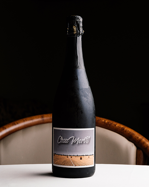 Bottiglia di Franciacorta Blanc de Blancs Monogram con etichetta personalizzata “CasaMerlò”, sul tavolo del ristorante Da Sacerno