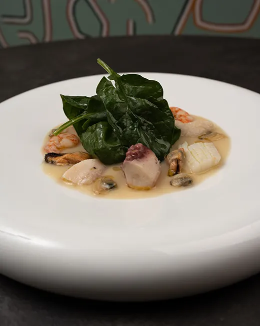 Insalata di mare su crema di verdure con insalata di spinaci, impiattata al ristorante di pesce Da Sacerno a Bologna