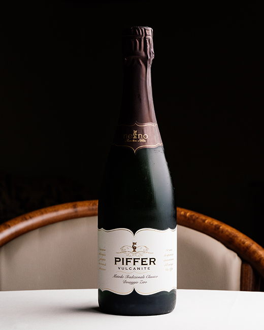 Bottiglia di bollicina metodo classico del Trentino-Alto Adige Piffer “Vulcanite” Dosaggio Zero, sul tavolo del ristorante Da Sacerno