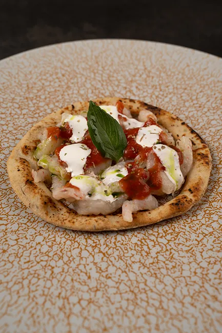 Pizza di gamberi crudi con pomodoro e mozzarella, impiattata al ristorante di pesce Da Sacerno a Bologna